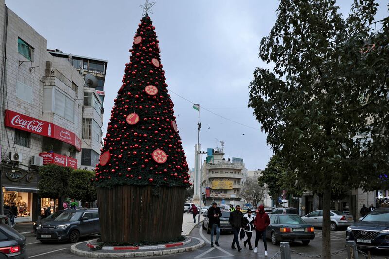 Palestinians walk by a Christmas tree on a cold day in the West Bank city of Ramallah. AFP
