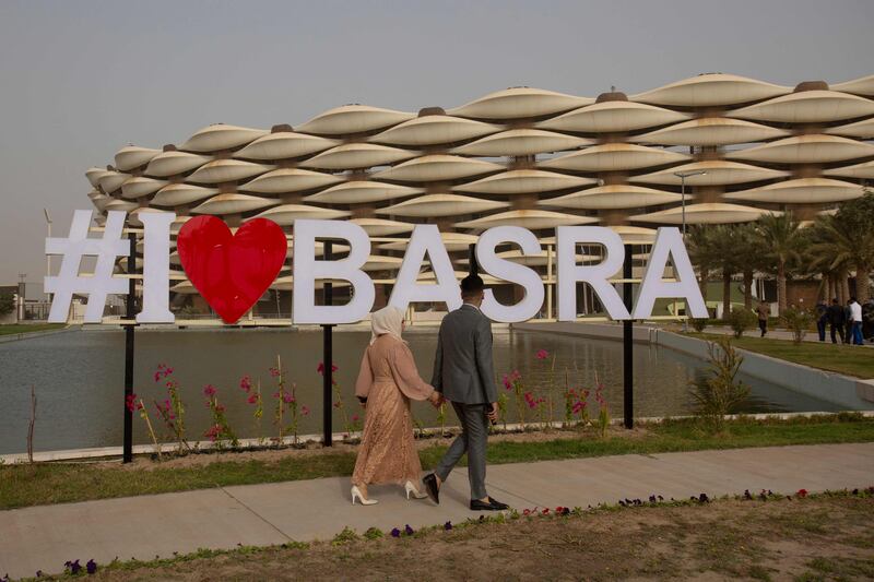 People walk in front of Basra International Stadium.