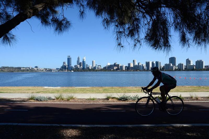 A cyclist rides alongside the Swan River past the city skyline in Perth, Australia. Carla Gottgens / Bloomberg

