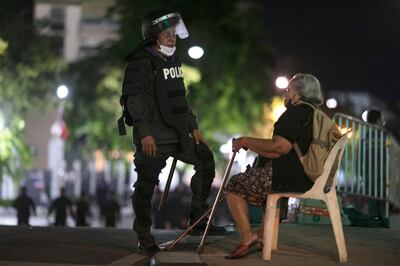 A riot policeman talks with an elderly women as they disperse pro-democracy protesters outside the Government House in Bangkok, Thailand, Thursday, Oct. 15, 2020. Thousands of anti-government protesters gathered Wednesday for a rally at Bangkok's Democracy Monument being held on the anniversary of a 1973 popular uprising that led to the ousting of a military dictatorship, amid a heavy police presence and fear of clashes with political opponents. (AP Photo/Wason Wanichakorn)