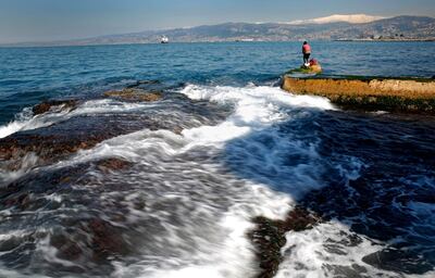 A Lebanese angler fishes as waves crash on the rocky coastal area off the Mediterranean Sea, in Beirut, Lebanon, Wednesday, Feb. 13, 2019. (AP Photo/Hussein Malla)