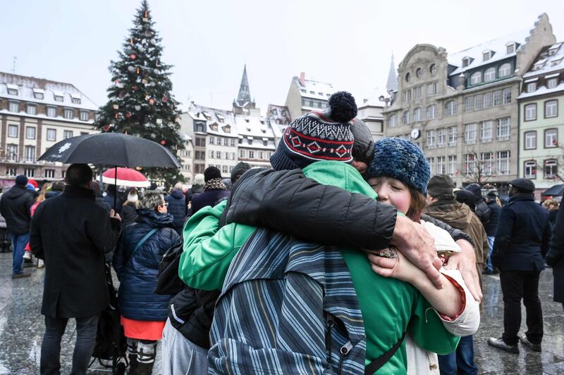 People hugh each others as they attend a gathering around a makeshift memorial at Place Kleber, in Strasbourg, on December 16, 2018 to pay a tribute to the victims of Strasbourg's attack. Four people were killed and 12 wounded when a lone gunman, identified as Cherif Chekatt, 29, opened fire on shoppers near the Christmas market, on December 11, 2018, according to French officials. / AFP / SEBASTIEN BOZON
