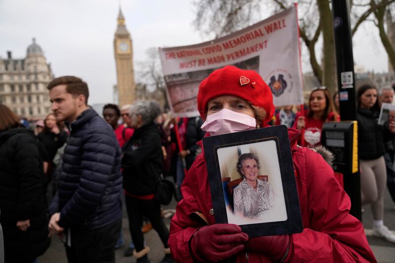 A woman holds a photograph of a family member who died as she takes part in a march from the National Covid Memorial wall to Downing Street in London. AP Photo