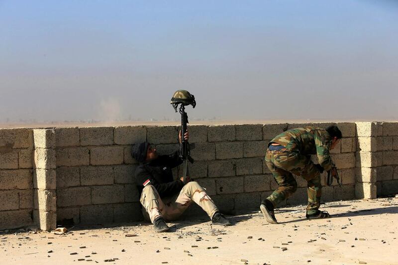 An Iraqi soldier uses his helmet to distract the opposing sniper during clashes with ISIL at the south of Mosul. Alaa Al-Marjani / Reuters