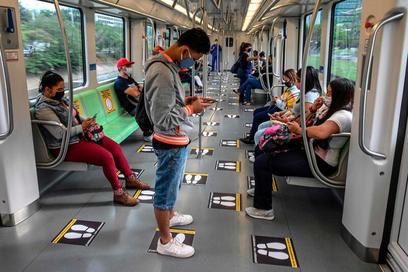 People wear face masks and stand on special marks as a practice of social distancing in Medellin, Colombia.  AFP