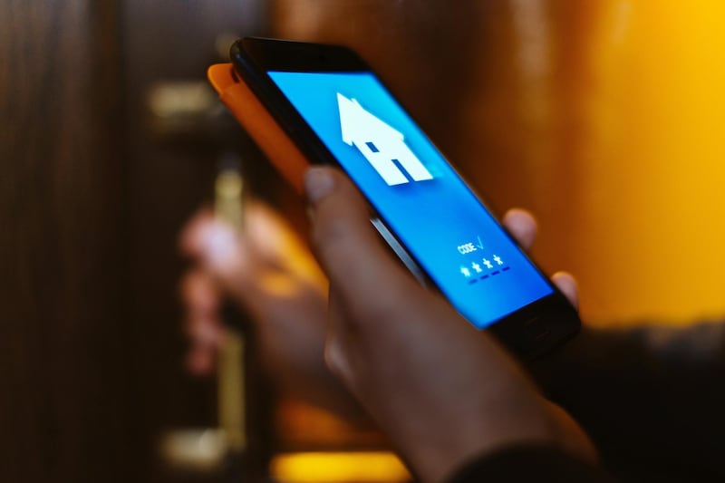 Woman using home app to open the door of her house with her smart phone, close-up.