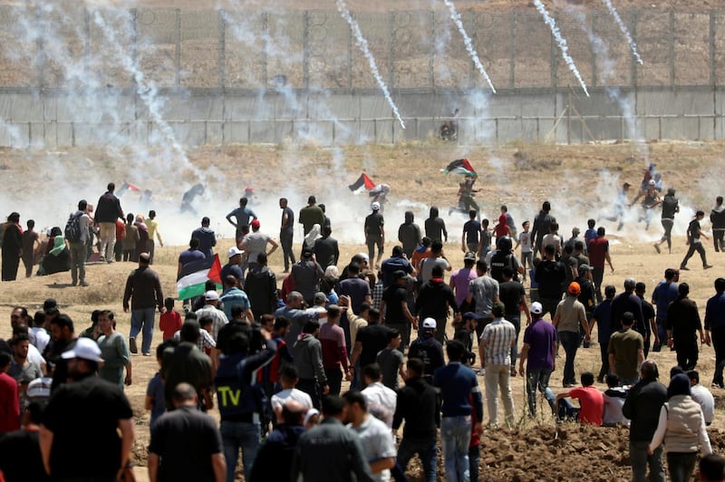 Palestinian demonstrators run for cover from tear gas canisters fired by Israeli forces during a protest marking the 71st anniversary of the 'Nakba'. Reuters