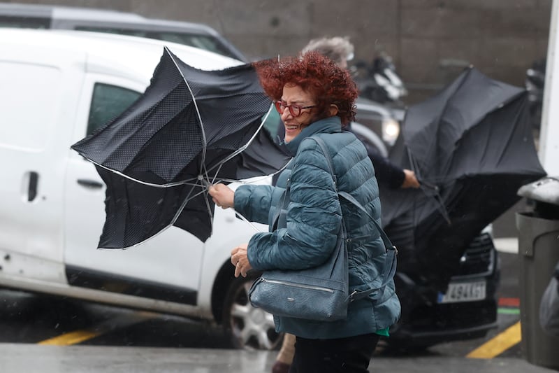 Struggling with an umbrella as severe winds hit central Madrid. EPA
