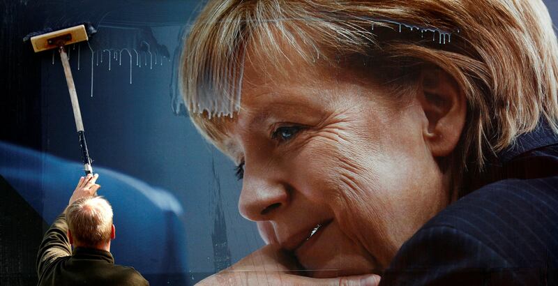 A worker pastes up an election campaign poster for the upcoming general elections of the Christian Democratic Union party (CDU) with a headshot of German Chancellor Angela Merkel in Berlin, Germany September 12, 2017. REUTERS/Fabrizio Bensch