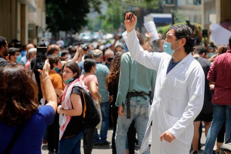 A Lebanese physician takes photos as former employees of the American University Medical Center react during a demonstration outside the hospital. AFP