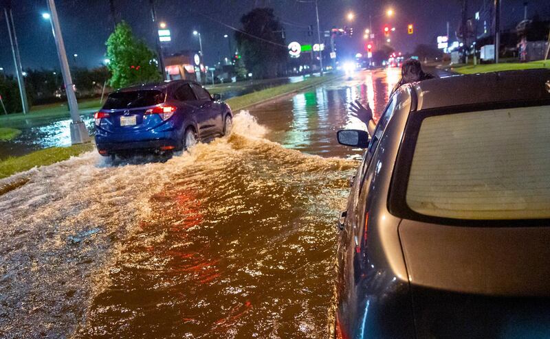 A motorist whose car stalled in flood waters in Slidell, Louisiana, gestures to a passing driver to slow down. AP