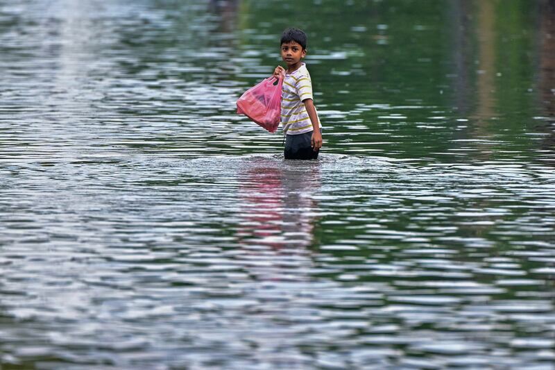 A boy wades through a flooded street after heavy rains in Malwana on the outskirts of Colombo. AFP