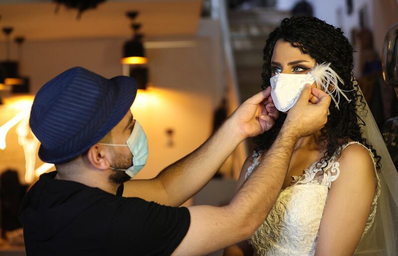 A model wears a face mask to help prevent the spread of the coronavirus, designed by Iraqi designer Ziad Tariq, left, at his workshop in Basra, Iraq. AP Photo