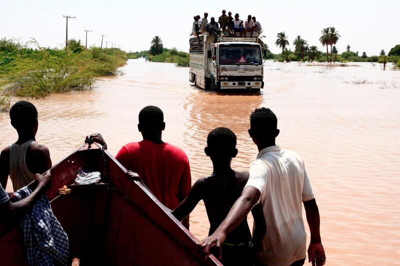 A truck carrying Sudanese villagers drives through a flooded street in Wad Ramli village on the eastern banks of the Nile river. AFP