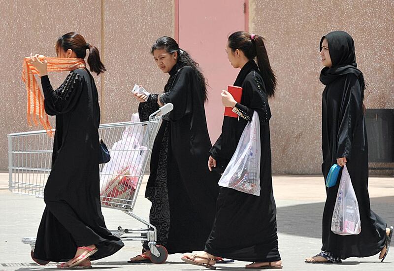 Filipina domestic workers carry shopping bags as they walk out of a mall in Riyadh. AFP