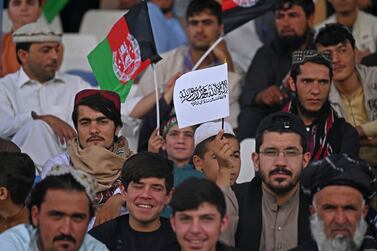 Spectators hold Afghanistan's and Taliban flags as they watch the Twenty20 cricket trial match being played between two Afghan teams 'Peace Defenders' and 'Peace Heroes' at the Kabul International Cricket Stadium in Kabul on September 3, 2021.  (Photo by Aamir QURESHI  /  AFP)