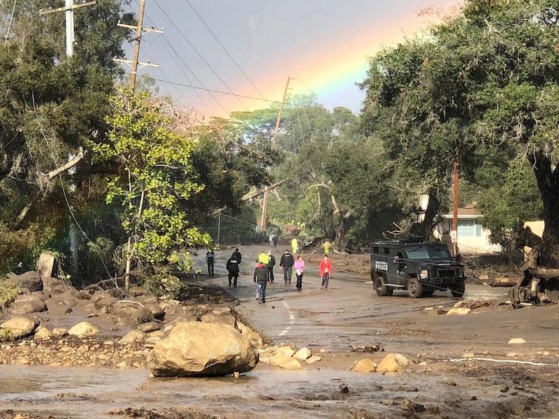 A rainbow forming above Montecito while law enforcement and the curious survey the destruction on Hot Springs Road following heavy rains in Montecito, California. Mike Eliason / Santa Barbara County Fire / EPA