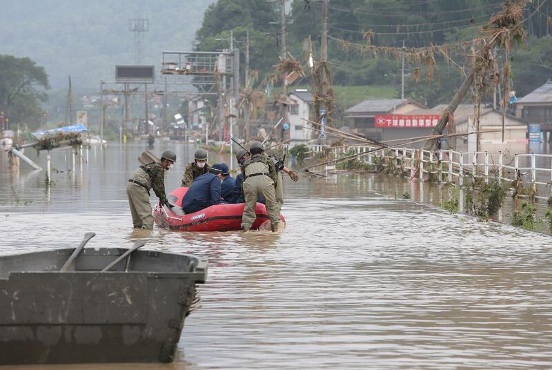 Japan Self-Defence Forces and police officers handle an inflatable boat to join rescue operations at a nursing home following heavy rain in Kuma village, Kumamoto prefecture. AFP