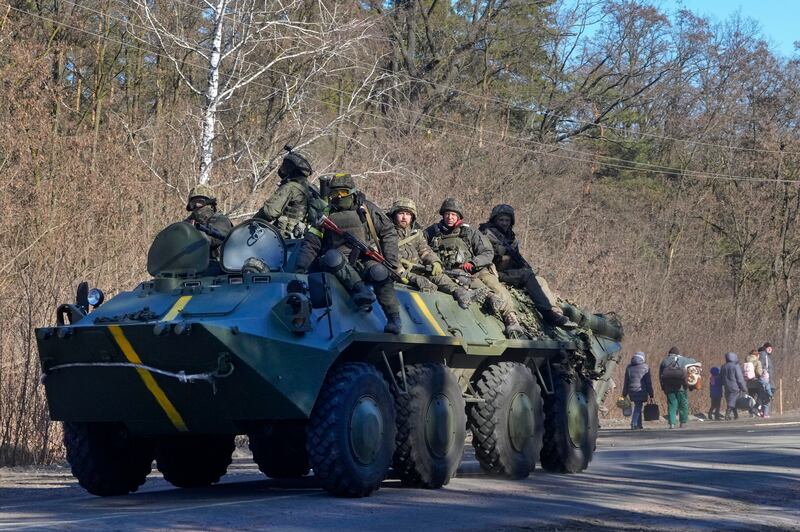 Ukrainian soldiers pass people fleeing the conflict in the Vyshgorod region close to Kyiv. AP Photo / Efrem Lukatsky