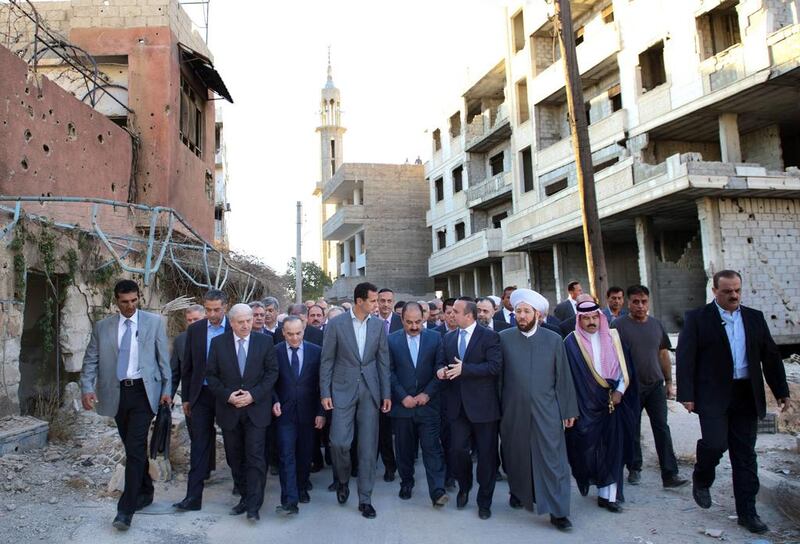 Syrian President Bashar Al Assad walking on a street alongside officials after performing the morning Eid Al Adha prayer at a mosque in a government-controlled area of Daraya.  AFP PHOTO / HO / SANA