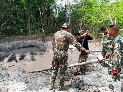 In this photo taken and released by the Department of Natural Park, Wildlife, and Plant Conservation Thursday, March 28, 2019, Thap Lan National Park rangers prepare to extract six baby elephants stuck in a muddy pond at Thap Lan National Park, Nakhon Ratchasima province, northeastern Thailand. Park rangers took five hours to dig out a path to save six elephant calves after they were found trapped in a muddy pond. (Department of Natural Park, Wildlife, and Plant Conservation via AP)