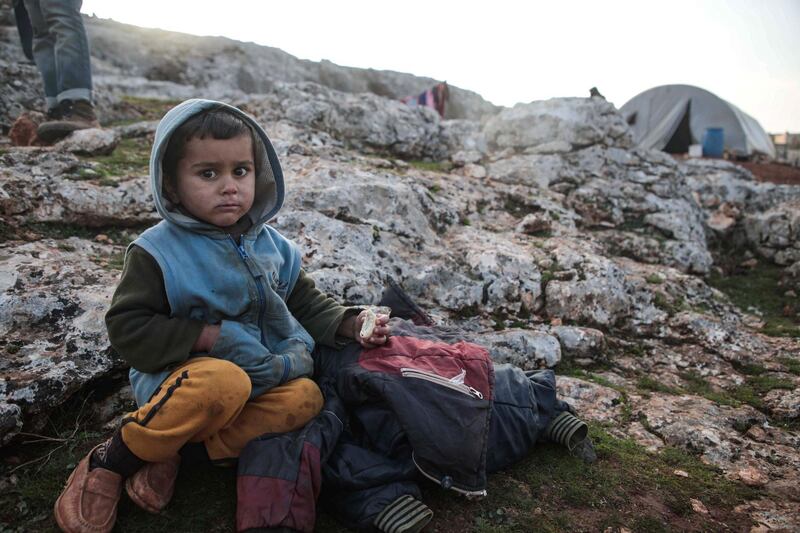 A displaced Syrian child from the south of Idlib province holds a piece of bread while sitting out in the open in the countryside west of the town of Dana in the northwestern Syrian region on December 23, 2019.  / AFP / Aaref WATAD
