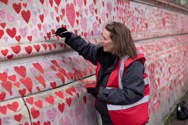A woman adds hearts to the National Covid Memorial Wall near St Thomas' Hospital in London. Getty Images