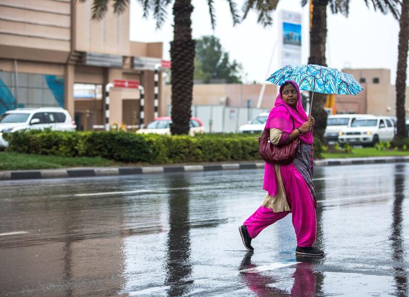 A woman with an umbrella crosses the street at the Hor Al Anz area, Dubai. Victor Besa for The National