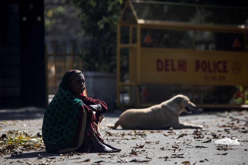 A woman sits next to a dog on a deserted street during the first day of a 21-day government-imposed nationwide lockdown in New Delhi.  AFP