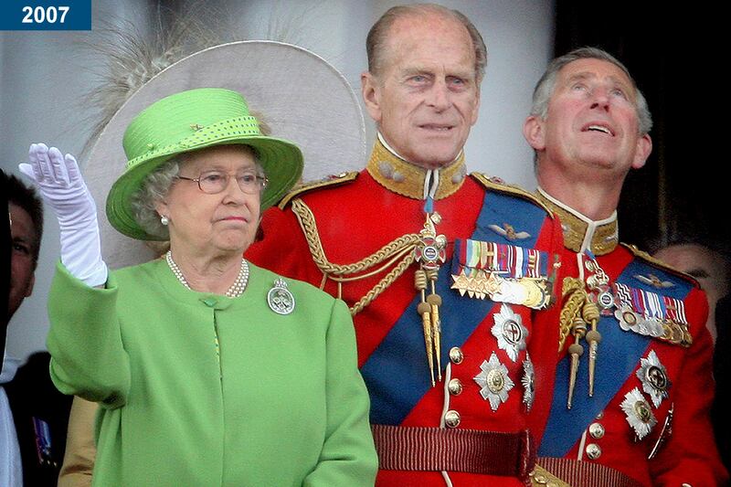 2007: A less-than-impressed queen raises her hand during a downpour as she stands with Prince Philip and Prince Charles on the balcony of Buckingham Palace after the Trooping the Colour ceremony.