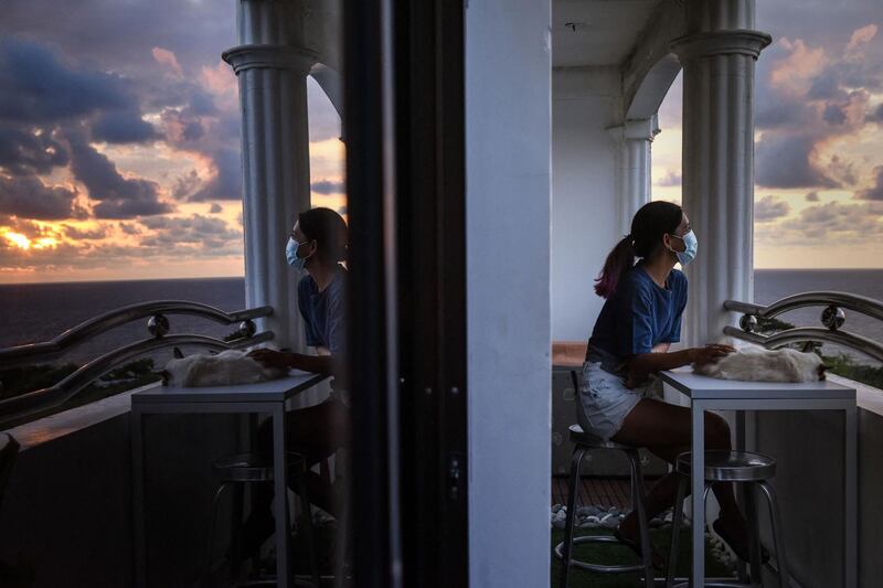 This photo taken on June 1, 2021 shows Tanya Mariano sitting at the porch at her apartment in the town of San Juan, La Union province, north of Manila. Many digital workers in congested Manila, fearing Covid-19 and fed up with lockdowns and restrictions, are escaping to largely deserted nature hotspots to do their jobs -- injecting much-needed money into communities dependent on outside visitors. - TO GO WITH AFP STORY: PHILIPPINES-HEALTH-VIRUS-LEISURE-ECONOMY, FOCUS BY ALLISON JACKSON
 / AFP / Maria Tan / TO GO WITH AFP STORY: PHILIPPINES-HEALTH-VIRUS-LEISURE-ECONOMY, FOCUS BY ALLISON JACKSON
