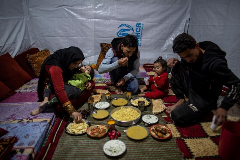 Raed Mattar, 24, centre, his wife Ayesha Al Abed, 21, and daughters Rahaf, 6, left, Rayan, 18 months old, and a friend, break their Ramadan fast in their tent at a makeshift refugee camp, in the town of Bhannine in the northern Lebanese city of Tripoli. AP Photo