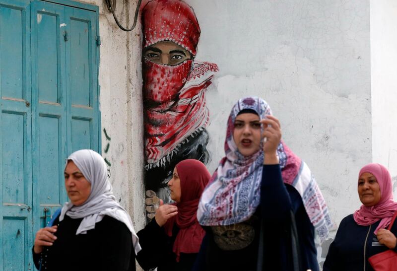 Palestinians walk past graffiti on a wall in the Al Arub refugee camp. AFP