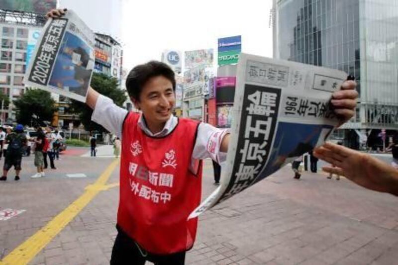 A vendor hands out free copies of a special newspaper edition printed to mark the announcement of Tokyo as the host of the 2020 Olympic Games.