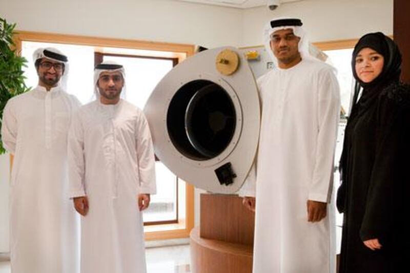 Dubai, United Arab Emirates - June 2 2013 - (L-R) Mohammed Bin Neshooq, Ahmed Abdelrazzaq Abdullah, khalif Sultan Zowayed and Amel Abdulla Amin, all employees, pose for a portrait next to a model of DubaiSat-1 at the Emirates Institution for Advanced Science & Technology (EIAST) speaks to The National. DubaiSat-1 was launched in July of 2009. (Razan Alzayani / The National)