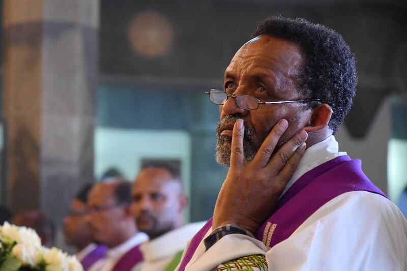 A priest looks on as relatives and mourners attend a memorial at a Catholic church in Addis Ababa. EPA
