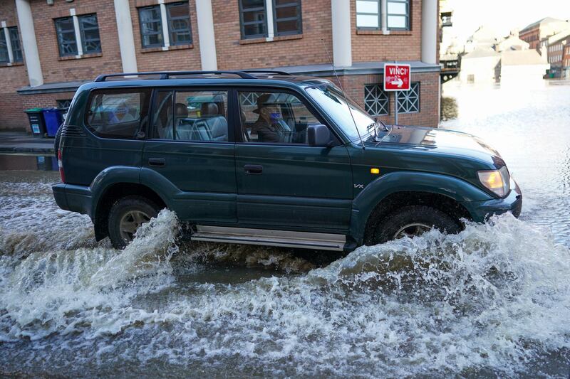 A driver works his way down a street as the River Ouse in York floods. Getty Images