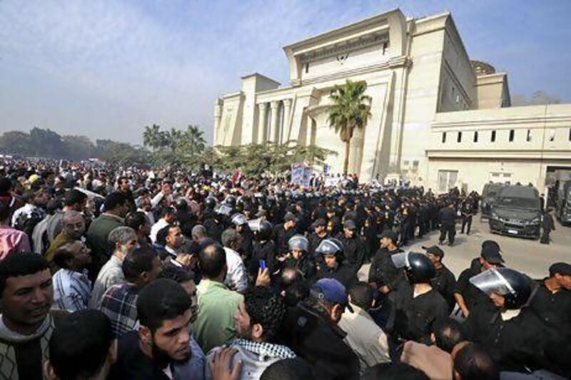 Riot police form a cordon as thousands of Mohammed Morsi’s supporters surround the Supreme Constitutional Court yesterday to prevent judges from entering and ruling on the legitimacy of the nation's Islamist-dominated constituent assembly.
