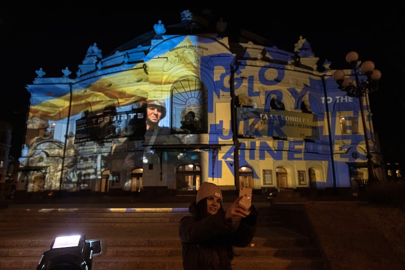 A woman takes selfies in front of The National Opera of Ukraine, illuminated by Swiss artist Gerry Hofstetter. Getty