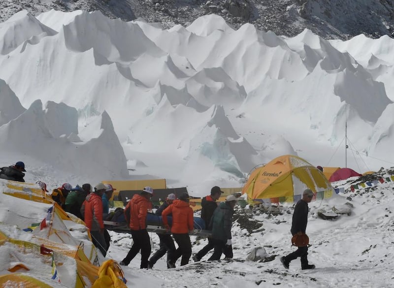 Rescue team personnel carry an injured person towards a rescue helicopter at Everest Base Camp on April 26, 2015, a day after an avalanche triggered by an earthquake devastated the camp. Roberto Schmidt/AFP Photo
