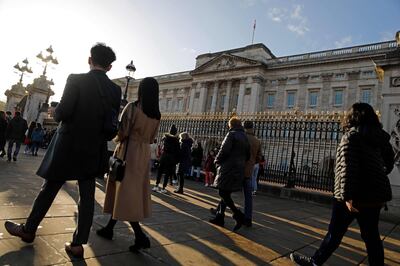 Tourists walk past the front of Buckingham Palace in London on January 9, 2020, following the announcement that Britain's Prince Harry, Duke of Sussex and his wife Meghan, Duchess of Sussex, plan to step down as "senior" members of the Royal Family. Britain's Prince Harry and his wife Meghan stunned the British monarchy on Wednesday by quitting as front-line members -- reportedly without first consulting Queen Elizabeth II. In a shock announcement, the couple said they would spend time in North America and rip up long-established relations with the press. Media reports said the Duke and Duchess of Sussex made their bombshell statement without notifying either Harry's grandmother the monarch, or his father Prince Charles. / AFP / Tolga AKMEN
