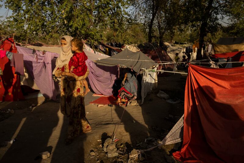 A woman holds a child at a camp for displaced people in Kabul. AP