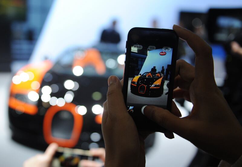 A visitor takes a photo of a Bugatti Veyron sports car on media day at the Shanghai auto show in Shanghai on April 20, 2013. Global car makers on April 20 showed off hundreds of gleaming models in glitzy demonstrations ahead of the Shanghai auto show, as they compete for attention from the world's largest market -- China. AFP PHOTO / Peter PARKS
 *** Local Caption ***  952315-01-08.jpg