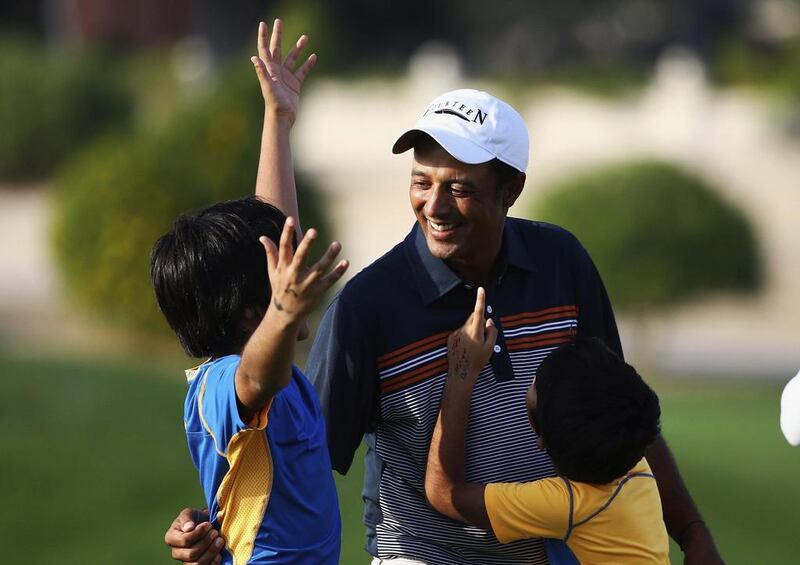 Arjun Atwal hugs his children Krishna and Shiva after winning the Dubai Open at The Els Club on Sunday. Francois Nel / Getty Images