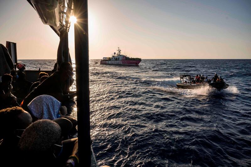 Migrants rescued by Sea-Watch 4 a week ago in the international waters off Libya watch crew members of civil sea rescue ship Sea-Watch 4 on inflatable boats help migrants to get off the rescue ship funded by British street artist Banksy "Louise Michel" (background) off the coast of Malta, on August 29, 2020. 
background) An Italian coastguard vessel on August 29, 2020 had rushed to "Louise Michel" after it sent out a call for help with more than 200 migrants onboard, and took in 49 of the most vulnerable people on board. The Sea-Watch 4 vessel, that has a clinic and already rescued 201 migrants onboard and is itself in search of a host port, also arrived and took over 150 migrants from "Louise Michel".  - Germany OUT
 / AFP / Thomas Lohnes
