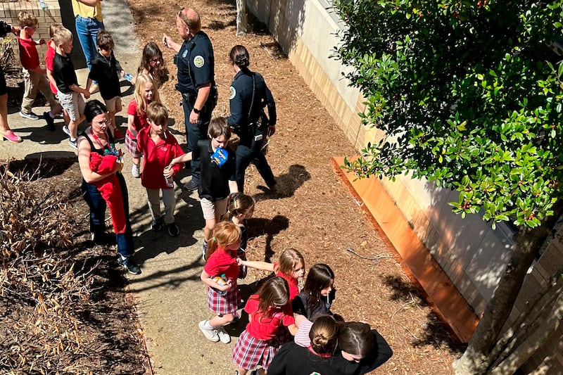 Pupils hold hands as they are taken to the church after the shooting. AP