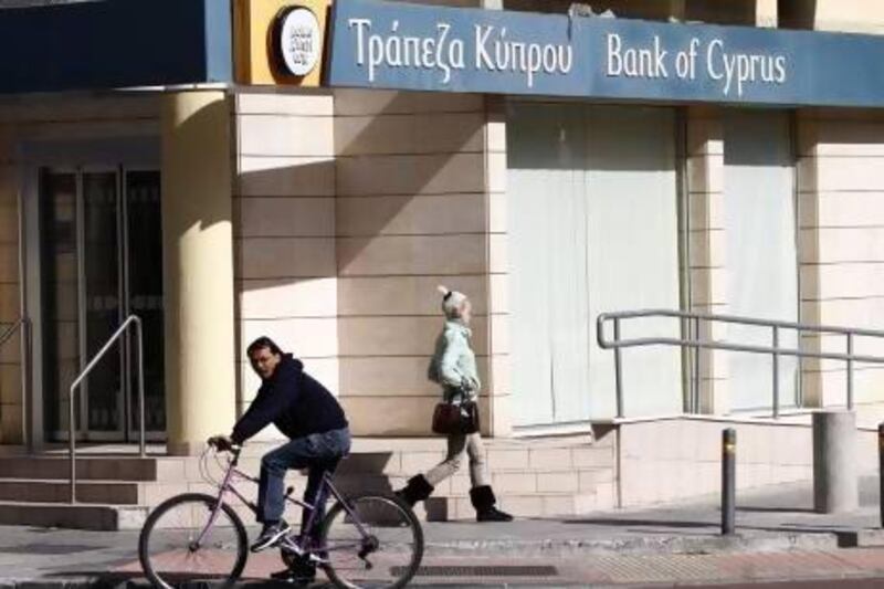 A woman walks past a boarded-up branch of the Bank of Cyprus in Nicosia. The banks are to reopen early today.