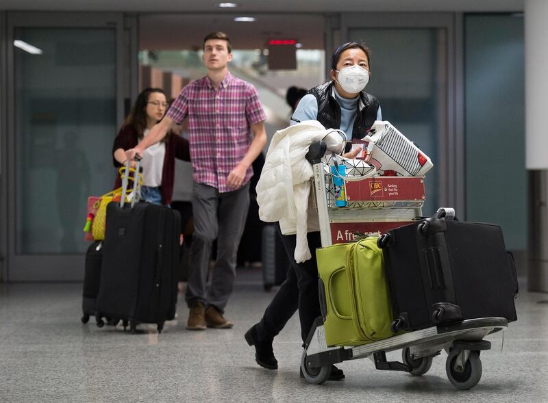 A woman wears a mask following the outbreak of a new virus as people arrive from the international terminal at Pearson International Airport in Toronto.  AP