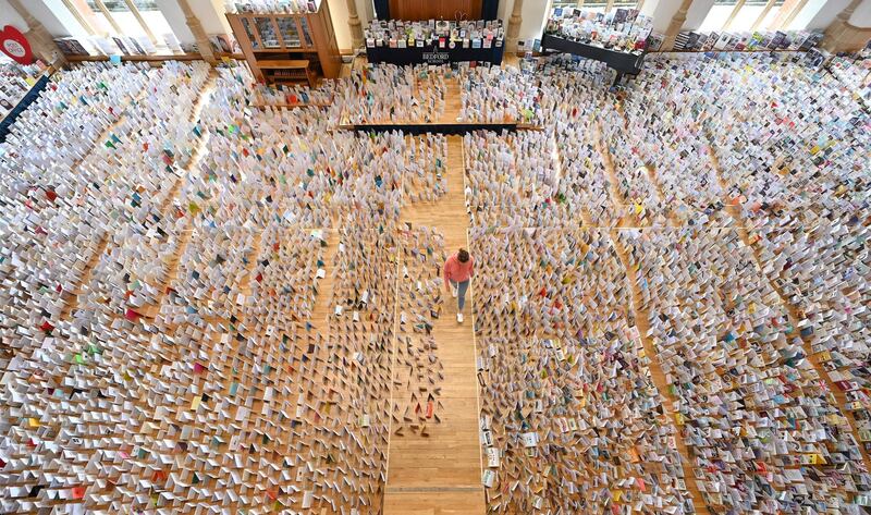 Mandy Alison poses with a selection of over 125,000 birthday cards sent to Captain Tom Moore, for his 100th birthday on April 30th, but displayed in the Great Hall of Bedford School, closed-down due to the COVID-19 pandemic, in Bedford, north of London, on April 28, 2020. - 99-year-old Moore captured the hearts of the UK after initially setting out to raise just £1,000 for Britain's National Health Service (NHS) following the novel coronavirus outbreak, by walking 100 laps of his 25-metre (82-foot) garden, but went on to brake the record for raising the most money in an individual charity walk -- more than £27 million ($33 million, 31 million euros). (Photo by JUSTIN TALLIS / AFP)