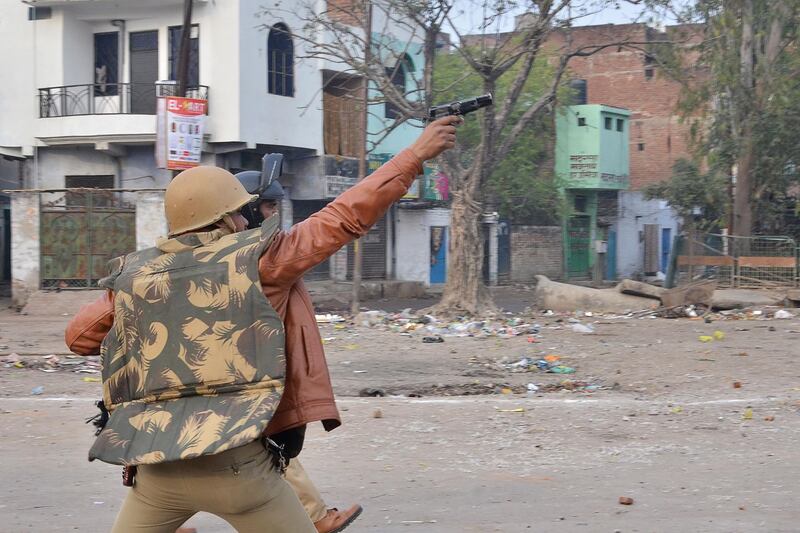 A police personnel aims his gun towards protesters during demonstrations against India's new citizenship law in in Kanpur.  AFP